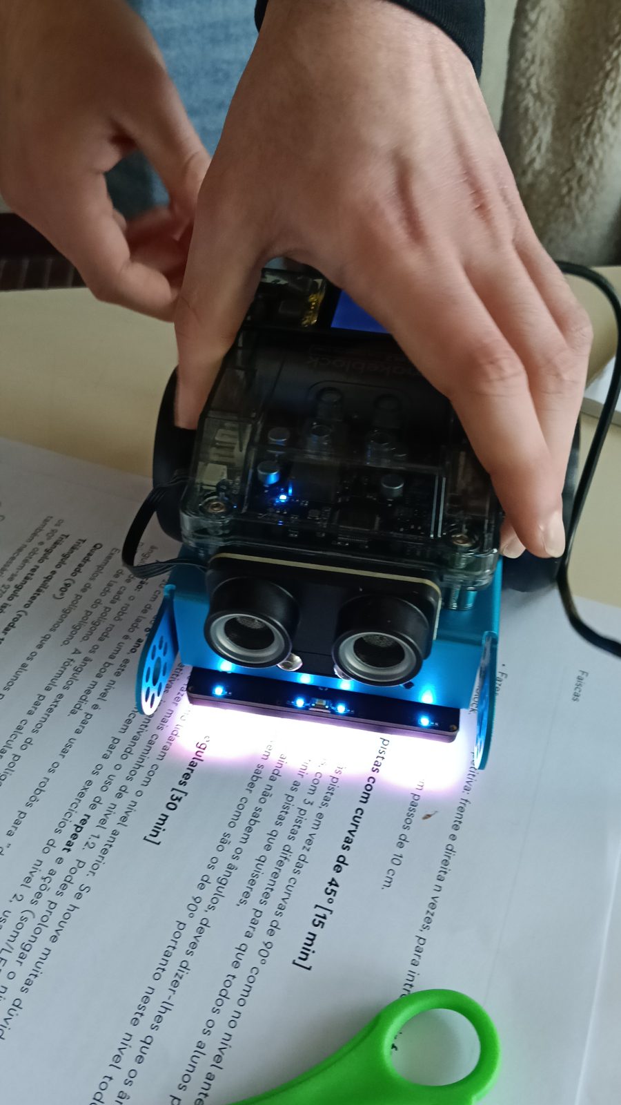 Mãos a pegar num robô com as luzes acesas